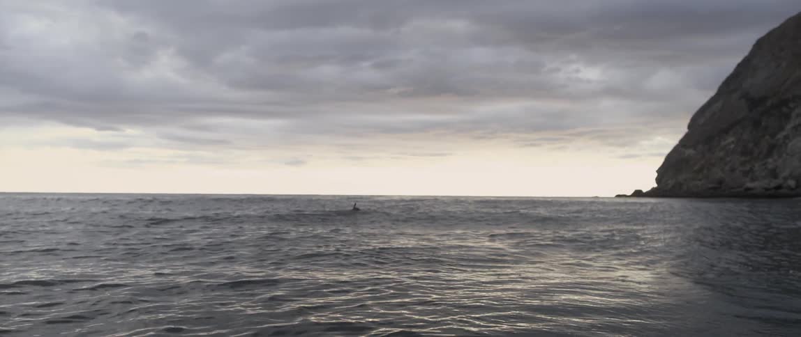 The water is rough with one person swimming ahead
