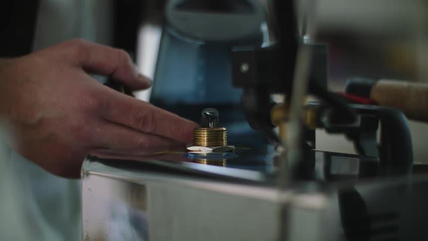 Closeup of a hand holding a container and pouring water into a small hole in a machine