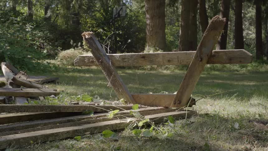 A man holding an axe and breaking a wooden table in an outdoor environment in the garden