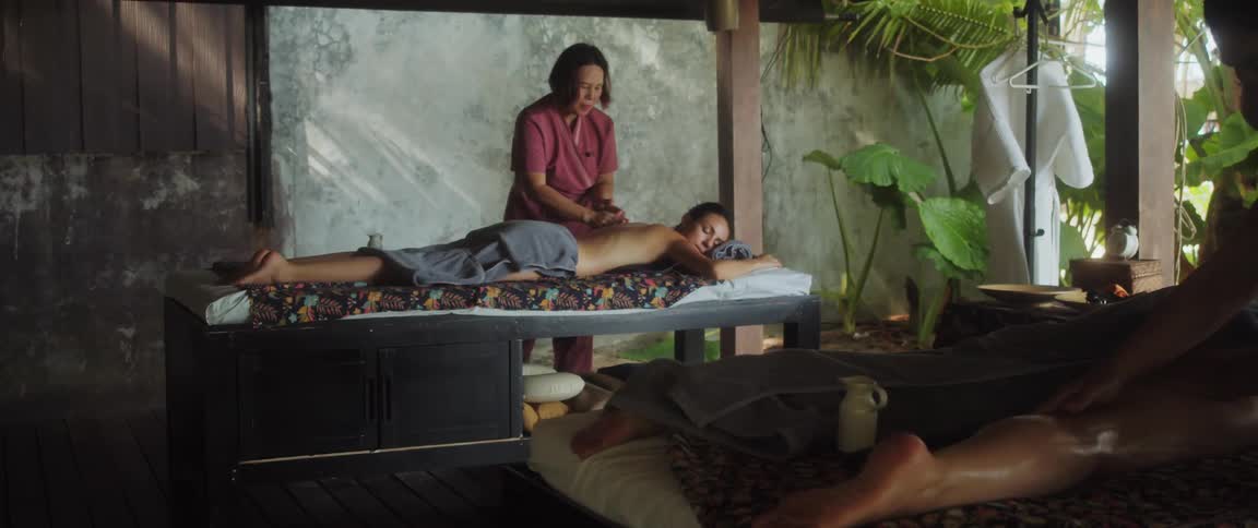Two people are getting massages lying on beds at a spa