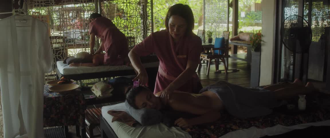 A masseuse rubbing a womens back while she lays on the table during the day at a spa