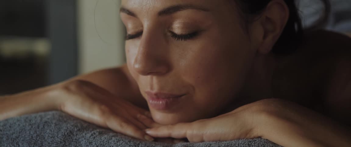 A woman closes her eyes while laying prone on massage table