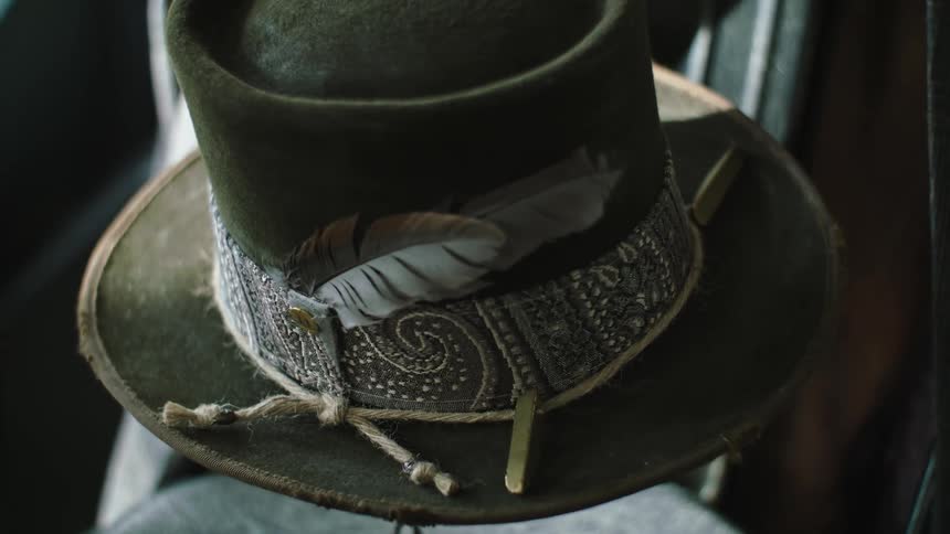 A green hat with a feather line design and a rope around it