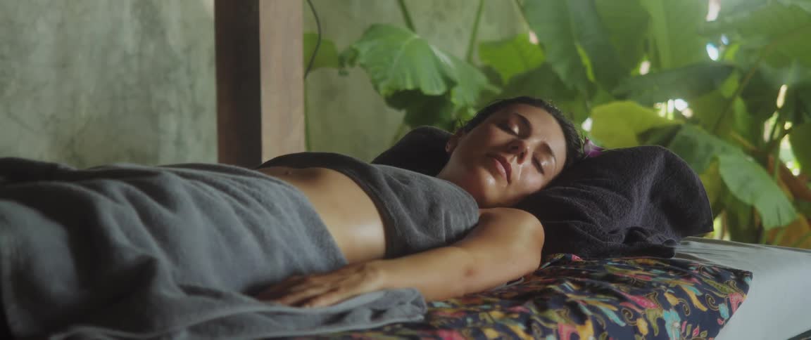 Woman sleeps on the bed in daytime with towels covering her private parts