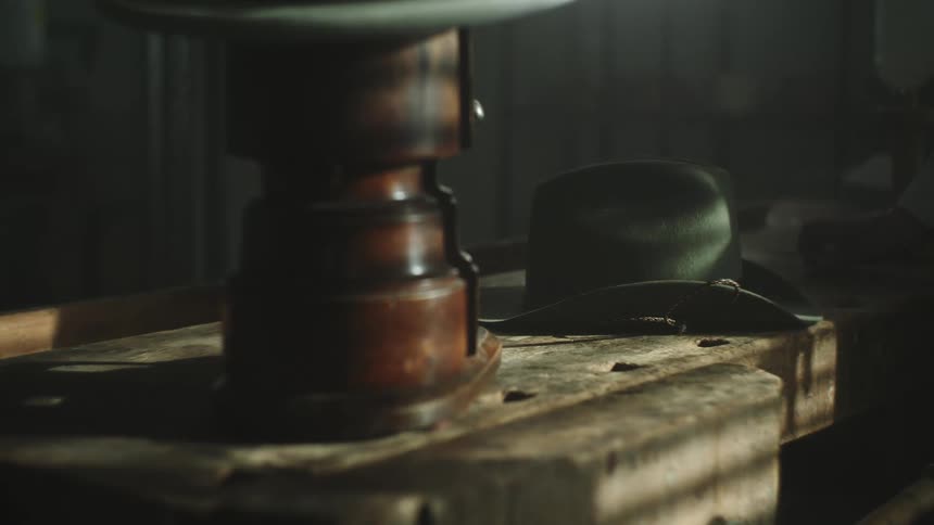 One person takes a cowboy hat off a table