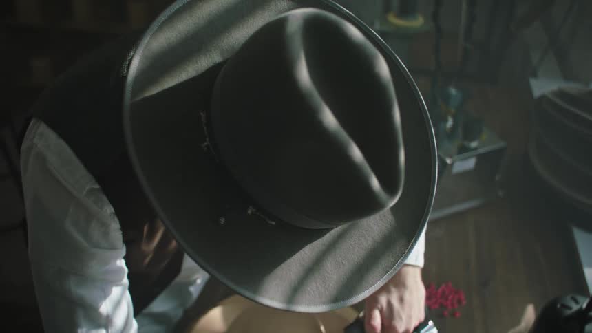 Hat maker irons hat rim with clothes iron
