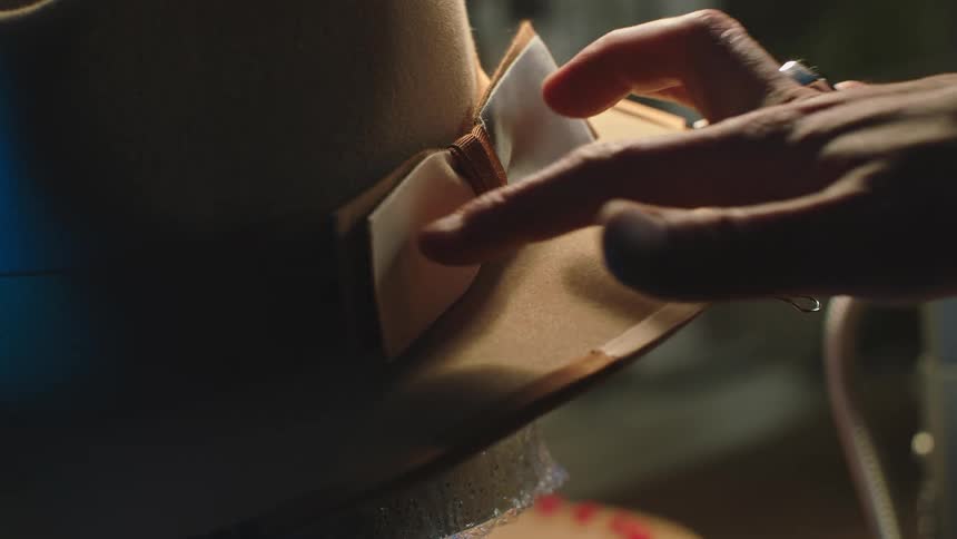 Close up of a hat with clips on the brim as a person places a bow on the hat
