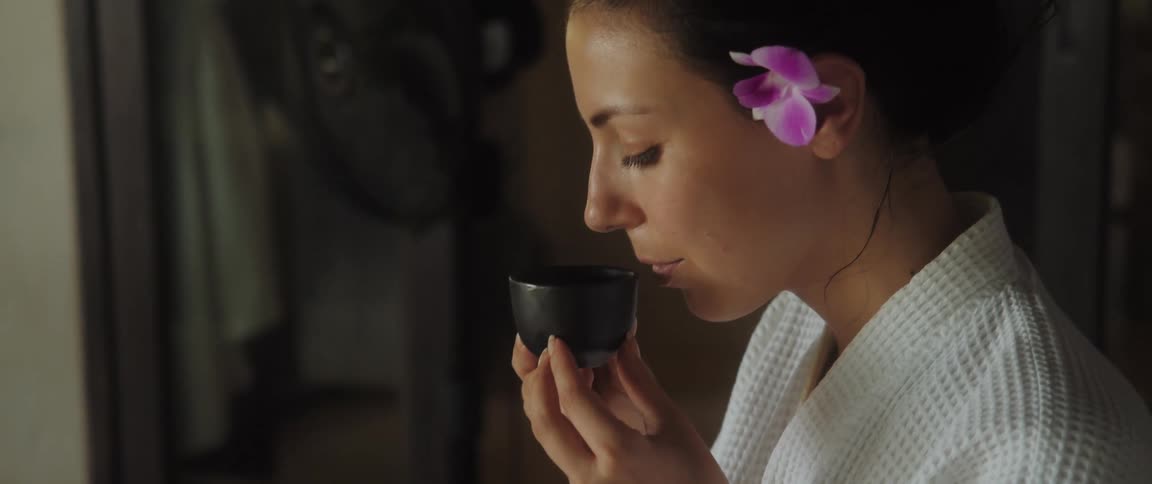 Slow motion of a woman drinking out of a small cup
