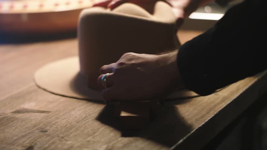 A person making a cowboy hat at a table