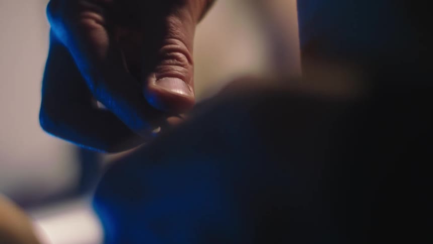The fingers of a human hand sewing an object