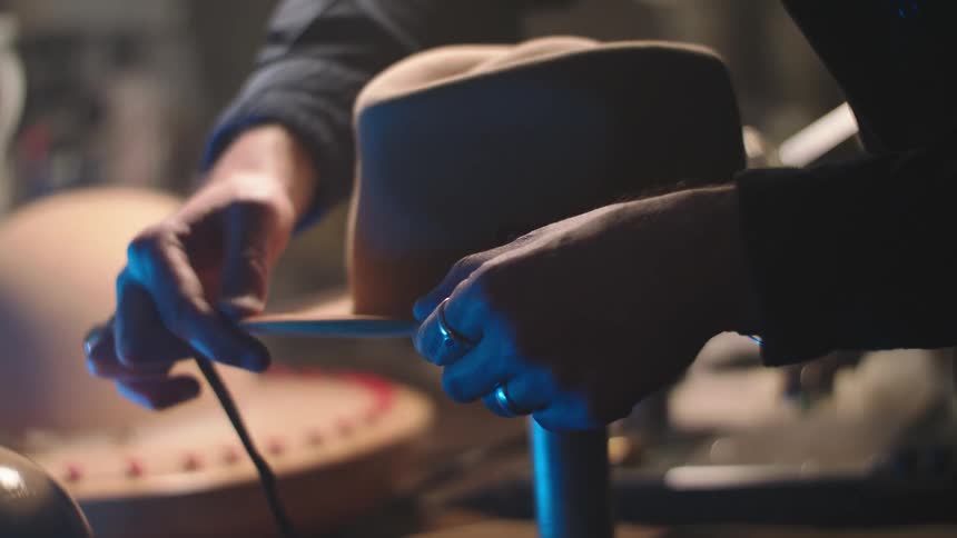 A person wearing a ring is making a cowboy hat