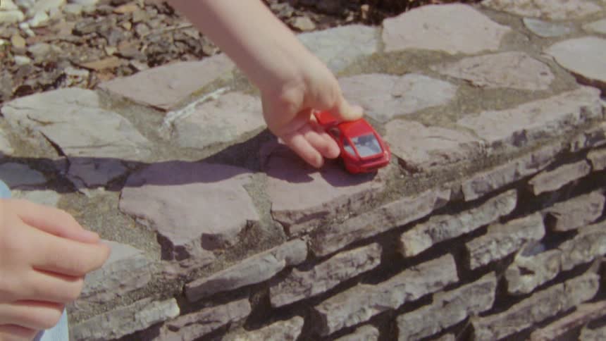 A child is playing with a toy car