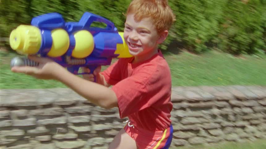 A child is running around the yard shooting a water gun