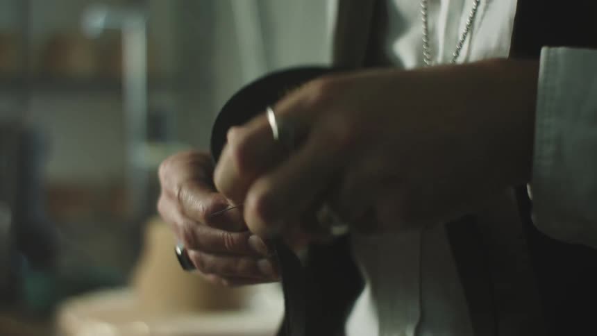 A persons hands passing a thread sewing an object