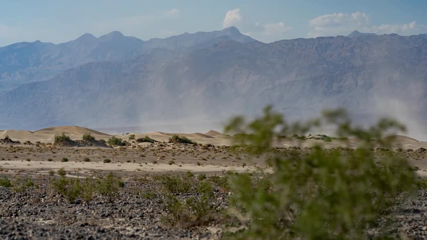 A small sand tornado passing through a desert region near the mountains