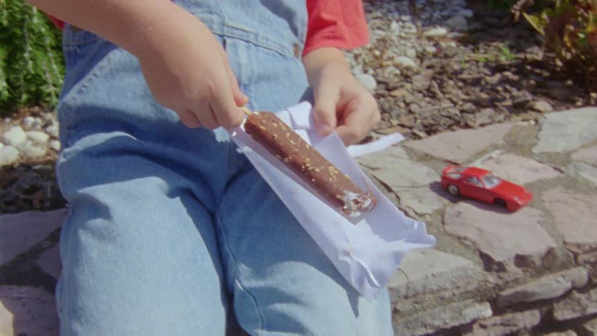 A male child licking a chocolate popsicle