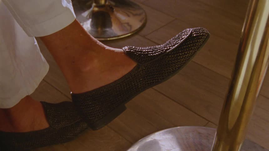 A crosslegged person moving their feet in formal shoes