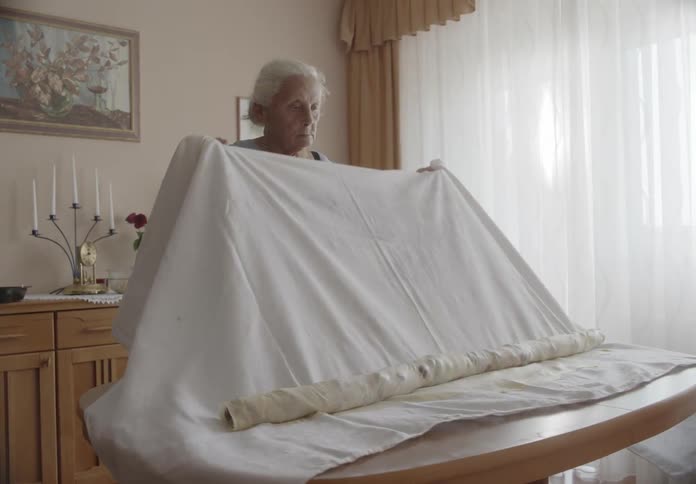 Elderly woman wrapping a cloth with fruits on top of a table