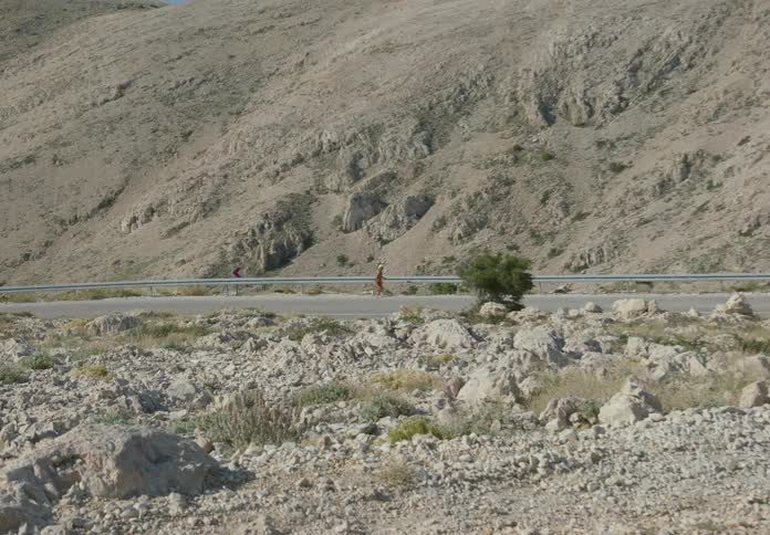 Man wearing a hat and shorts running alone on a tarred road
