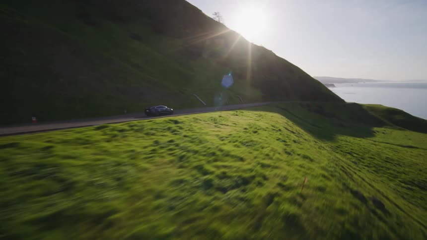 A car traveling fast along the coastline at sunrise