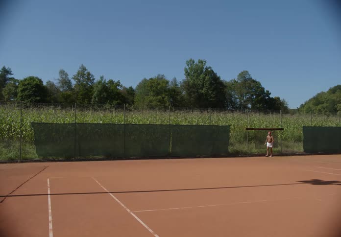 A man is tinkering with a tennis court fence