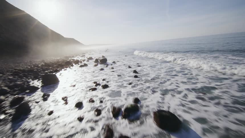 FPV drone view of a rocky coastline at sunrise