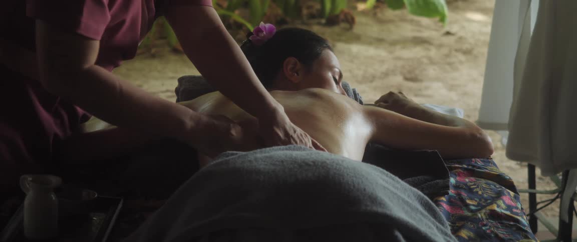 The masseur gently massages womans back