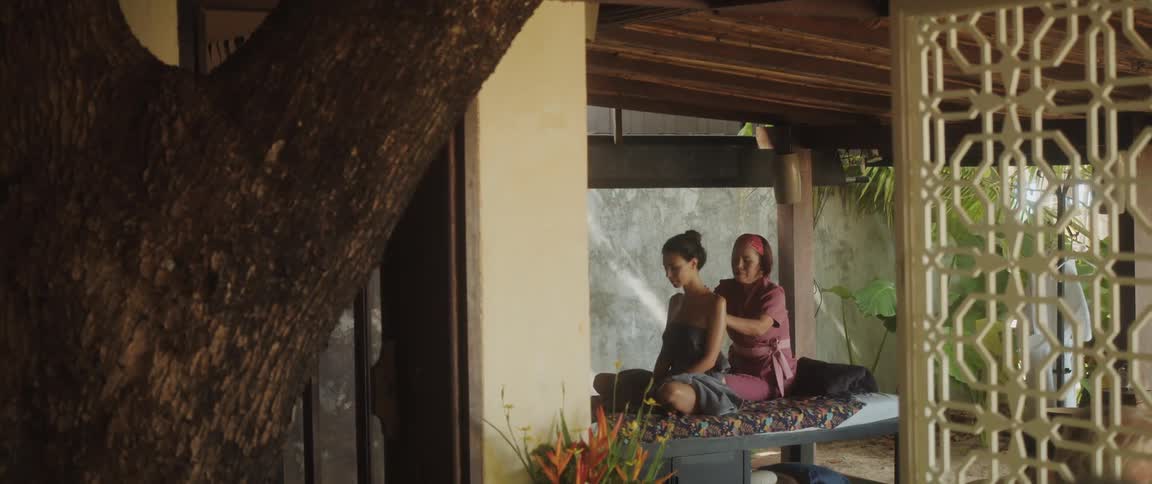Female masseur provides massage for woman sitting