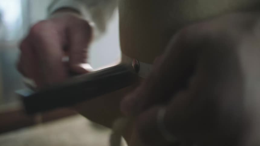 A person hammering a button to secure a band on a hat