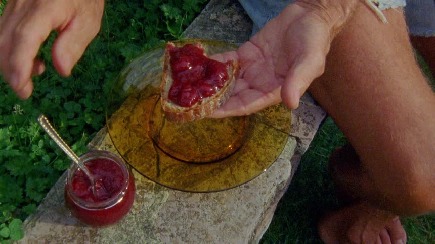 Elderly person preparing a bread with jelly
