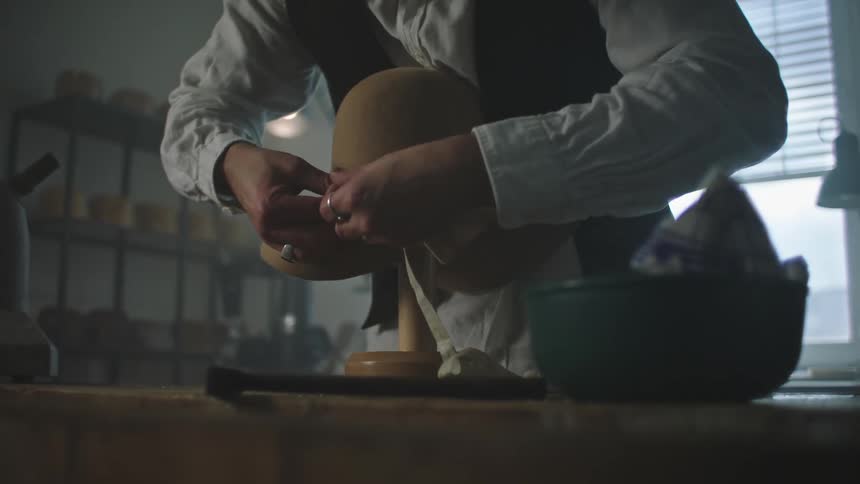 A person makes a hat in a factory during the day