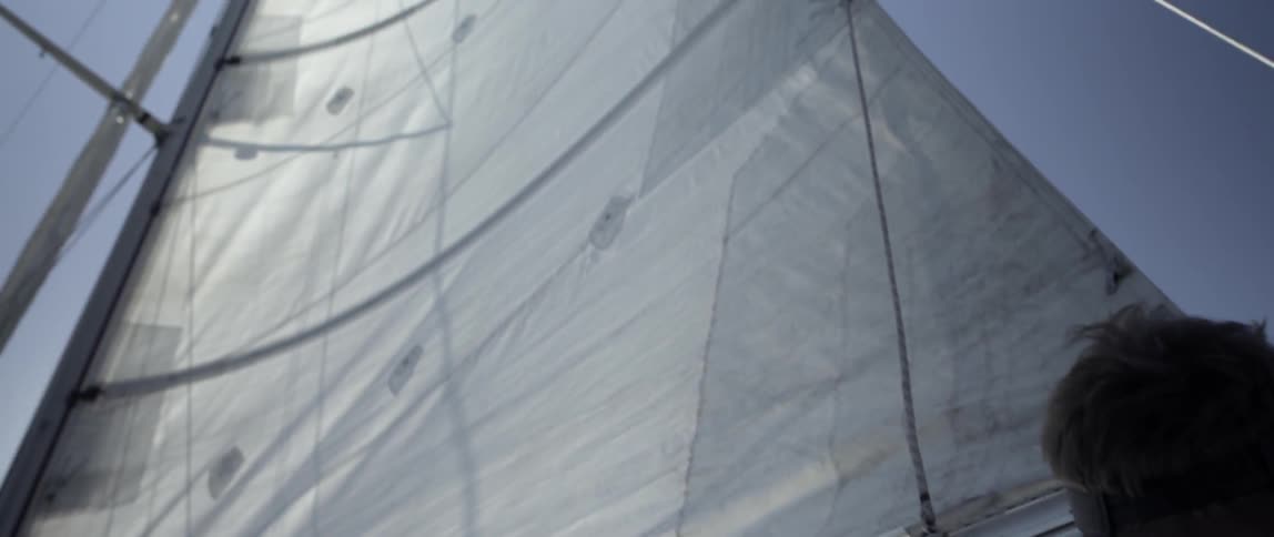 A man looks up at the sail on a boat