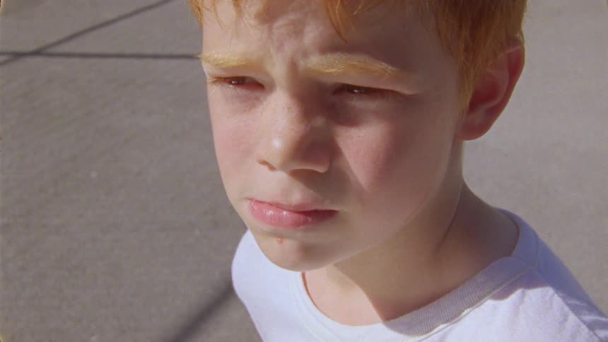 Portrait of a redhaired boy with a serious expression taking a deep breath