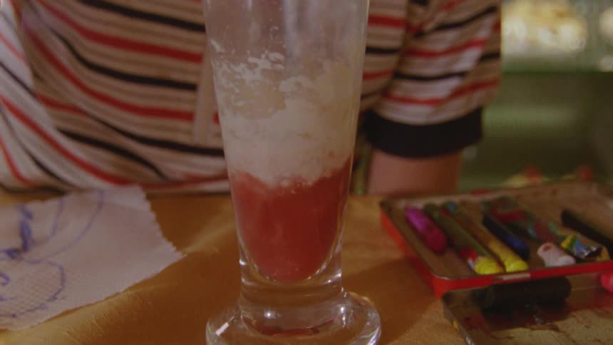 Child drinking juice from a glass with a straw