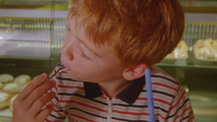 Child sitting in an establishment eating a piece of cake