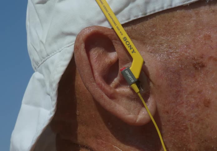 Elderly person with a device in his ear and a sweaty face