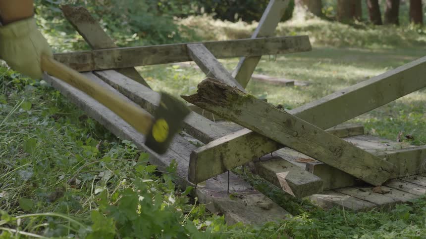 A person breaks a wooden structure in the garden