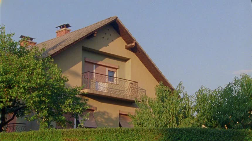 Exterior architecture of a house with chimneys and a yard with trees