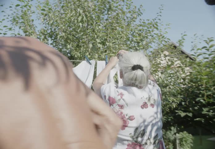 An elderly couple putting their laundry out to dry in a clothes line