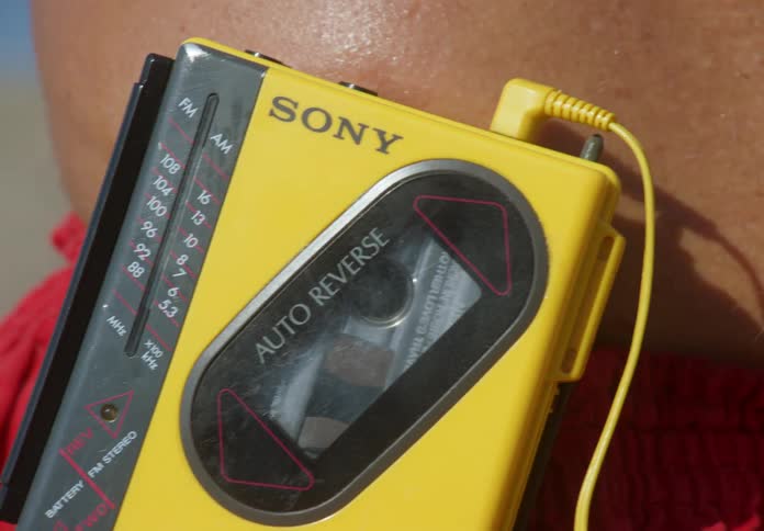 An old model electronic radio where a person presses a button with his finger