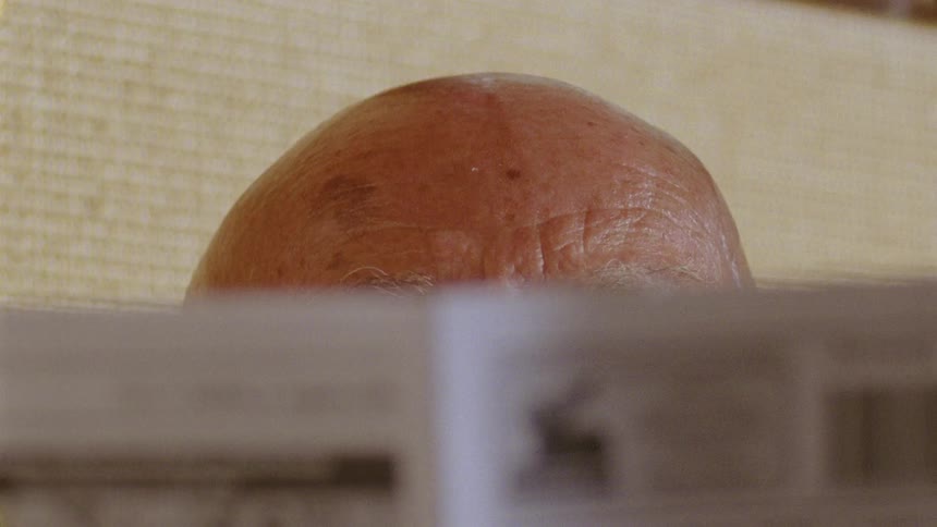 Closeup on the forehead of an elderly person reading a newspaper
