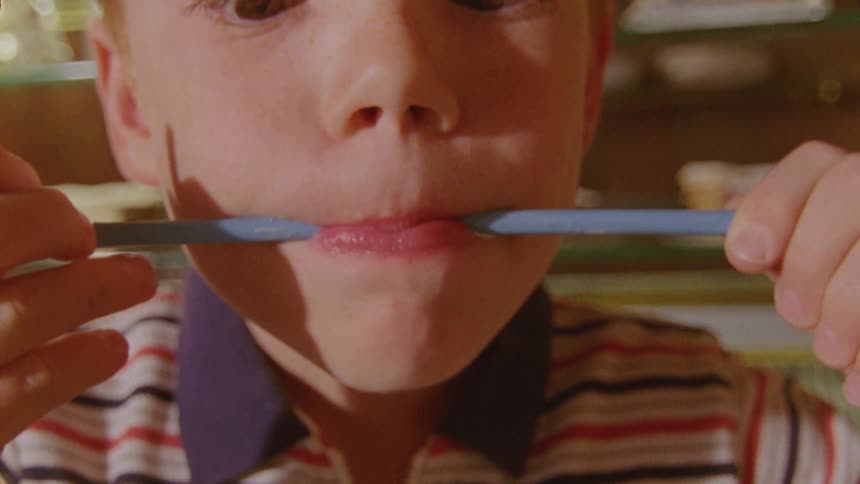 Boy with red hair licks blue drinking straw