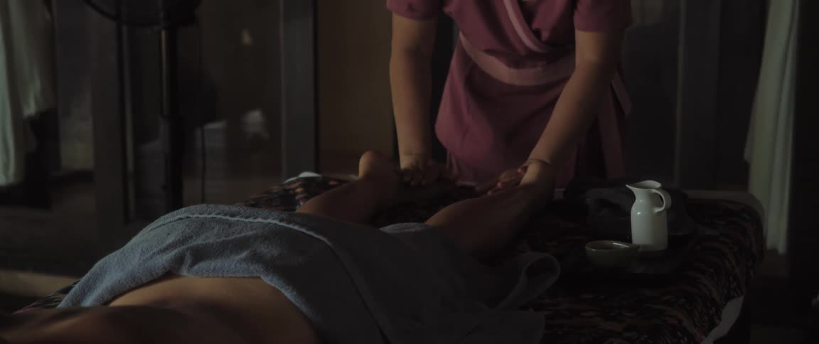 Woman rubbing the legs of another woman laying on the massage table in a room