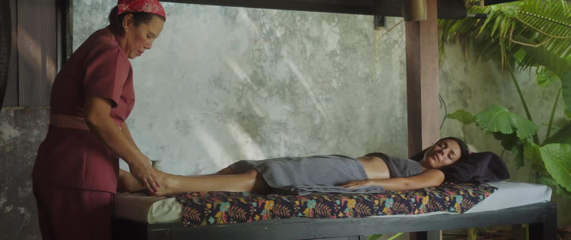 Woman lying on a spa bed while another woman massages her legs