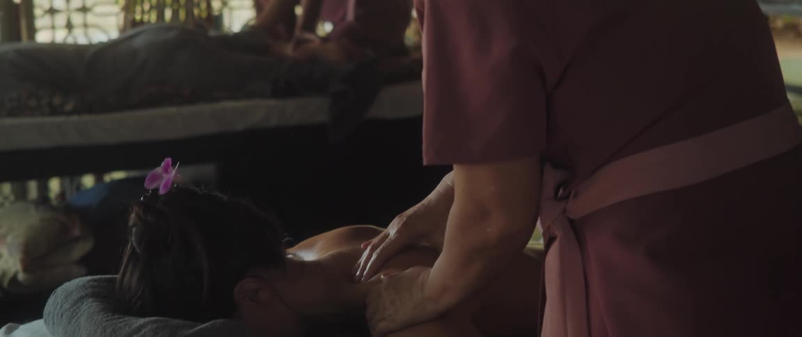 Woman massaging the back of a lady laying on the table in day time