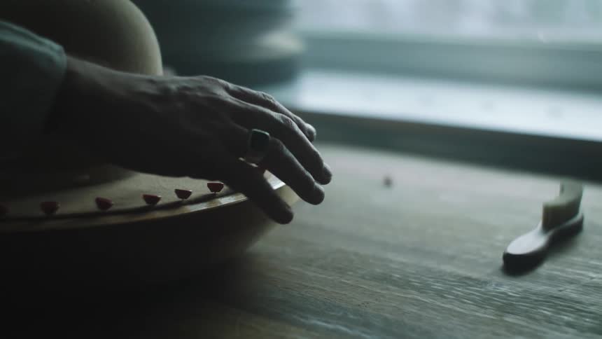 A man puts pins in the brim of a hat on a wooden board