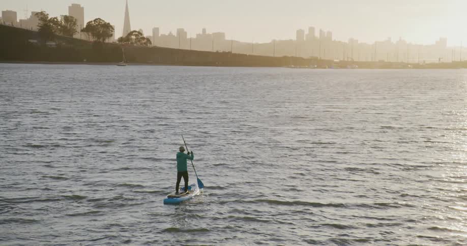 A person on a stand up paddle board with a city skyline in the background