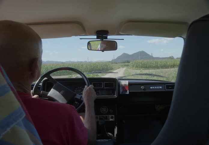 A man is driving down a dirt road in a mountain landscape