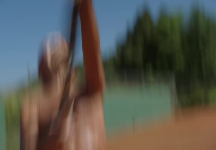 An elderly man playing tennis with a racket on a tennis court