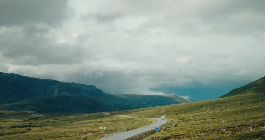 Rv travels along highway through valley between misty mountains on a cloudy day